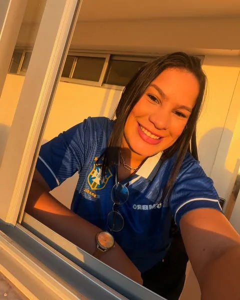 Aline Prado sorrindo em uma janela